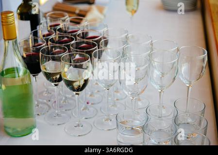 Moskau Russland - Juli 30 2023 - ordentlich angeordnete Weingläser, einige mit Rot- und Weißwein gefüllt, stehen neben Flaschen auf einer weißen Tischdecke bei an Stockfoto