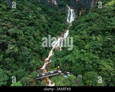 Das Bild zeigt den geheimen Wasserfall in Illukpelessa, Sri Lanka, umgeben von dichtem tropischem Grün. Das Wasser kaskadiert über zerklüftete Felsen in eine Tra Stockfoto