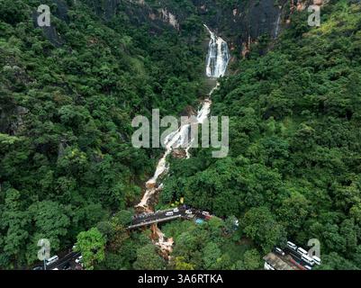 Das Bild zeigt den geheimen Wasserfall in Illukpelessa, Sri Lanka, umgeben von dichtem tropischem Grün. Das Wasser kaskadiert über zerklüftete Felsen in eine Tra Stockfoto