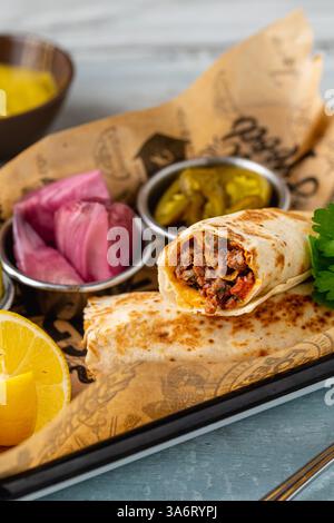 Türkischer Kebab Tantuni serviert mit Sauce und Gurken. Mersin Tantuni-Verpackung Stockfoto