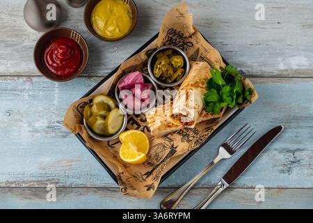 Türkischer Kebab Tantuni serviert mit Sauce und Gurken. Mersin Tantuni-Verpackung Stockfoto