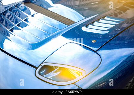 Modernes blaues Auto Nahaufnahme von Scheinwerfern und Sonnenstrahlen. Stockfoto