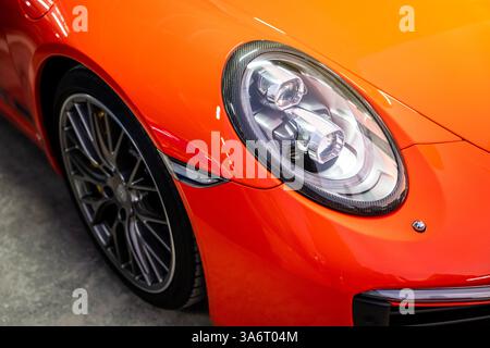Modernes rotes Auto Nahaufnahme von Scheinwerfern und Sonnenstrahlen. Stockfoto