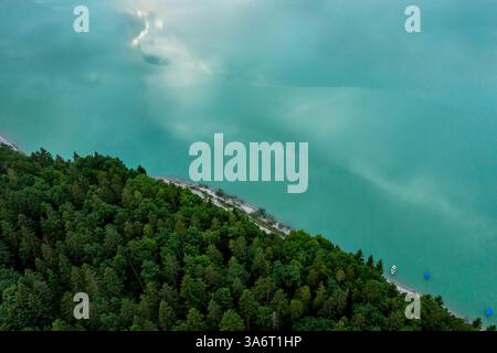 Blickpunkt der Drohne mit türkisfarbenem Wasser und Kiefernwäldern in Oberbayern, Deutschland Stockfoto