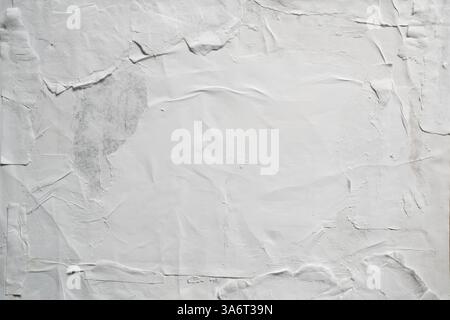 Ein strukturiertes weißes Poster mit Weizenpaste, verwitterter, leicht zerrissener Oberfläche, das Anzeichen von Verschleiß und Alterung zeigt. Stockfoto