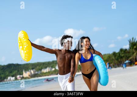 Interrassisches Paar, das einen romantischen Strandurlaub genießt und Liebe, Lachen und Zweisamkeit genießt Stockfoto