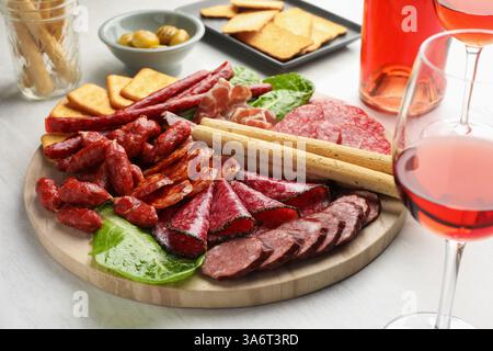 Verschiedene geräucherte Würstchen und andere Snacks serviert mit Wein auf weißem Tisch, Nahaufnahme Stockfoto