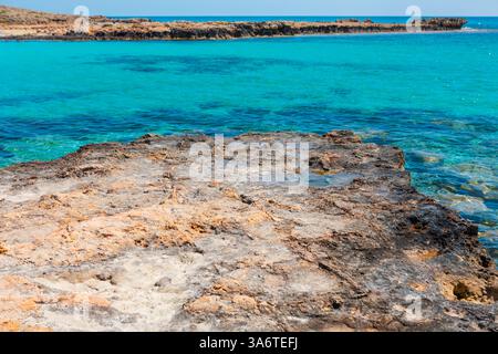 Küstenszene in Zypern mit zerklüfteter felsiger Küste und glitzerndem türkisfarbenem Wasser. Lebendiger Kontrast zwischen kristallklarem Wasser und strukturierten Felsen Stockfoto