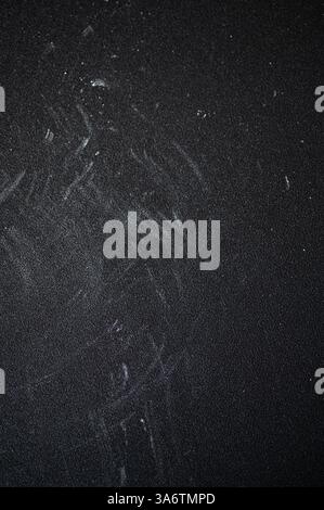 Mehl bestäubt eine dunkle Kreideplatte, strukturierte Oberfläche, die einen perfekten Hintergrund zum Backen schafft. Verstreutes weißes Pulver verleiht dem Besucher einen rustikalen, kulinarischen Touch Stockfoto
