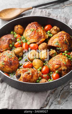 Hähnchenschenkel mit Pilzen und Gemüse in einer Pfanne auf dem Tisch in Nahaufnahme gebacken. Vertikal Stockfoto