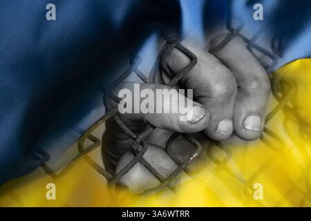 Hand einer älteren Frau auf einem Metallgitter vor dem Hintergrund der ukrainischen Flagge, Freiheit für Zivilisten Stockfoto