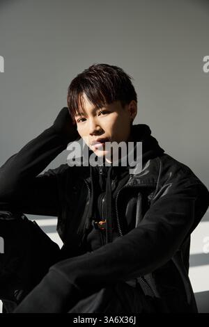 Ein hübscher asiatischer Mann in trendigem Outfit trifft in einer modernen Umgebung eine besinnliche Pose Stockfoto
