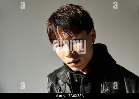 Ein junger Mann mit auffälligen Details zeichnet sich durch ein stilvolles Outfit in minimalistischer Umgebung aus. Stockfoto