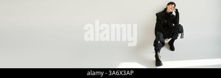 Ein gutaussehender junger Mann in trendiger Kleidung zeigt eine lässige Pose mit selbstbewusstem Ausdruck. Stockfoto