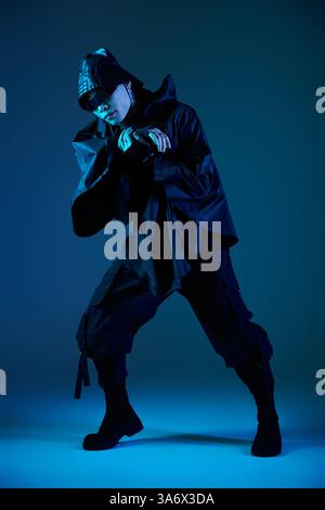 Ein hübscher asiatischer Mann posiert in einem auffälligen Outfit unter leuchtendem Blau. Stockfoto
