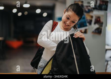 Junge Frau, die aufgeregt in ihren Rucksack schaut, in ungezwungener Umgebung Stockfoto