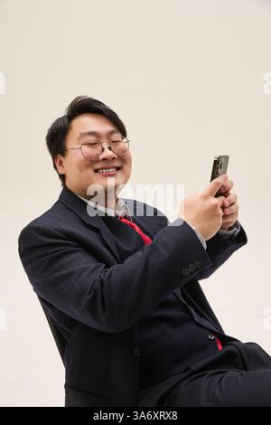 Porträt eines fröhlich lächelnden jungen asiatischen Mannes, in formeller Kleidung, Selfie vor weißem Hintergrund. Moderner Lifestyle. Stockfoto