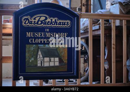 In der historischen Bruchmühle hängt ein Vintage-Backwarenschild aus dem Museumsdorf Cloppenburg mit einer traditionellen Fachwerkhausillustration. Stockfoto