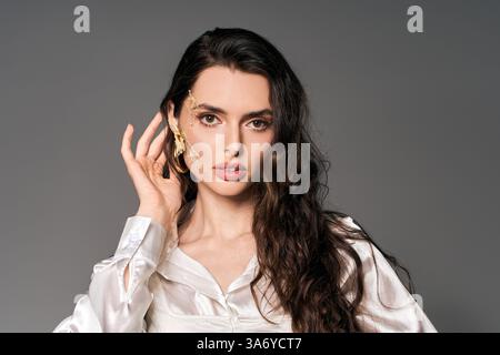Eine junge Frau, die braune Haare mit Blumen berührt, die Frühlingsessenz einfängt. Stockfoto
