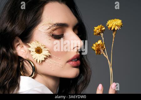 Eine junge Frau mit braunen Haaren zeigt Blumen und fängt das Wesen des Frühlings ein. Stockfoto