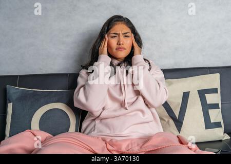 Gestresste Frau, die pochende Kopfschmerzen empfindet, Schläfen mit Fingern berührt, zu Hause an Migräne leidet Stockfoto