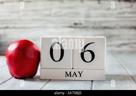 Kalenderblöcke aus weißem Holz mit dem Datum vom 6. Mai und einem roten Apfel für den Nationallehrertag. Stockfoto