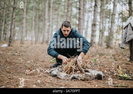 Ein Mann, der ein Lagerfeuer in einem Wald für ein Picknick im Freien vorbereitet Stockfoto