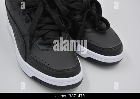 Schöne, junge Sportschuhe, schwarze Stiefel mit weißen harten Sohlen sind auf einem weißen plasti.. Warme Halbstiefel aus Leder mit Isolierung. Stockfoto