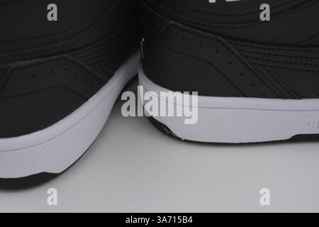 Schöne, junge Sportschuhe, schwarze Stiefel mit weißen harten Sohlen sind auf einem weißen plasti.. Warme Halbstiefel aus Leder mit Isolierung. Stockfoto