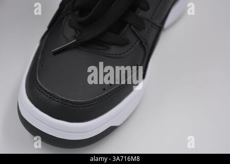 Schöne, junge Sportschuhe, schwarze Stiefel mit weißen harten Sohlen sind auf einem weißen plasti.. Warme Halbstiefel aus Leder mit Isolierung. Stockfoto