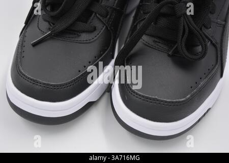 Schöne, junge Sportschuhe, schwarze Stiefel mit weißen harten Sohlen sind auf einem weißen plasti.. Warme Halbstiefel aus Leder mit Isolierung. Stockfoto