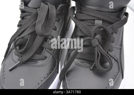 Schöne, junge Sportschuhe, schwarze Stiefel mit weißen harten Sohlen sind auf einem weißen plasti.. Warme Halbstiefel aus Leder mit Isolierung. Stockfoto