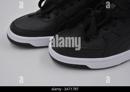 Schöne, junge Sportschuhe, schwarze Stiefel mit weißen harten Sohlen sind auf einem weißen plasti.. Warme Halbstiefel aus Leder mit Isolierung. Stockfoto