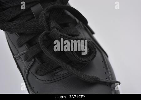 Schöne, junge Sportschuhe, schwarze Stiefel mit weißen harten Sohlen sind auf einem weißen plasti.. Warme Halbstiefel aus Leder mit Isolierung. Stockfoto