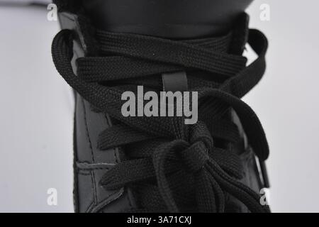 Schöne, junge Sportschuhe, schwarze Stiefel mit weißen harten Sohlen sind auf einem weißen plasti.. Warme Halbstiefel aus Leder mit Isolierung. Stockfoto