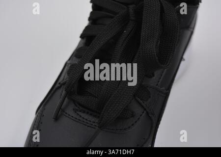 Schöne, junge Sportschuhe, schwarze Stiefel mit weißen harten Sohlen sind auf einem weißen plasti.. Warme Halbstiefel aus Leder mit Isolierung. Stockfoto