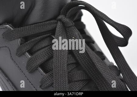 Schöne, junge Sportschuhe, schwarze Stiefel mit weißen harten Sohlen sind auf einem weißen plasti.. Warme Halbstiefel aus Leder mit Isolierung. Stockfoto