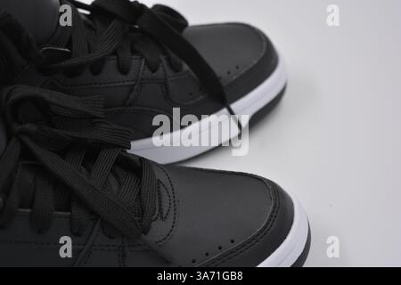 Schöne, junge Sportschuhe, schwarze Stiefel mit weißen harten Sohlen sind auf einem weißen plasti.. Warme Halbstiefel aus Leder mit Isolierung. Stockfoto