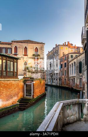 Venedig, Italien - 5. Februar 2025: Ein schmaler Kanal in Venedig, Italien, gesäumt von Gebäuden. Ein Balkon mit Blick auf das Wasser Stockfoto