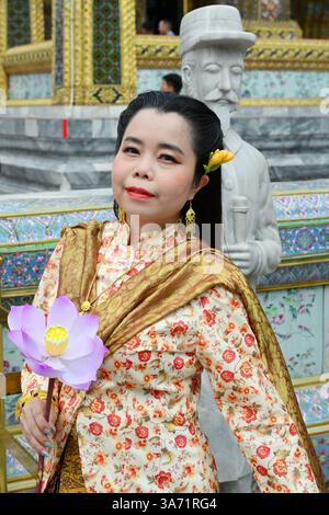 Elegante südasiatische Frau in traditioneller Kleidung hält eine Blume und fängt kulturelles Erbe, zeitlose Schönheit und anmutige Mode ein. Stockfoto