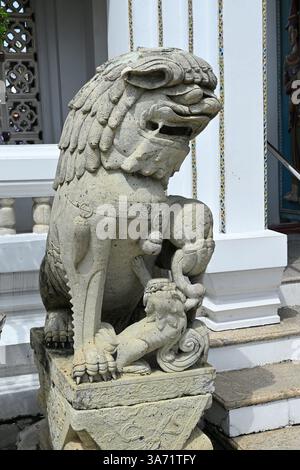 Verzierte Steinskulptur einer mythischen Wächterfigur, die auf einem Sockel sitzt und kunstvolle Handwerkskunst und asiatische architektonische Kunstfertigkeit zur Schau stellt. Stockfoto