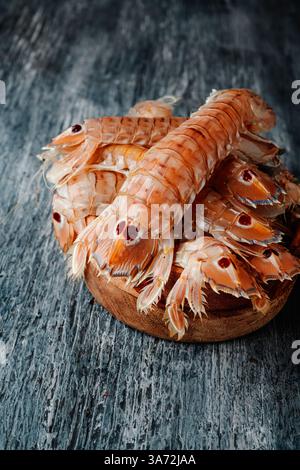 Ein paar Squilla-Mantis, eine Art von Mantis-Garnelen, die auf spanisch als galeras bekannt ist, auf einem grauen rustikalen Holztisch Stockfoto