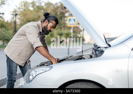 Indianer konzentrierten sich unter der Haube, um den Motor auf der Straße zu reparieren Stockfoto