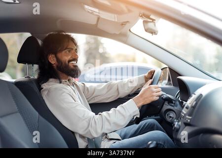 Lächelnder indischer Mann, der Auto fährt und lächelt, freut sich Stockfoto