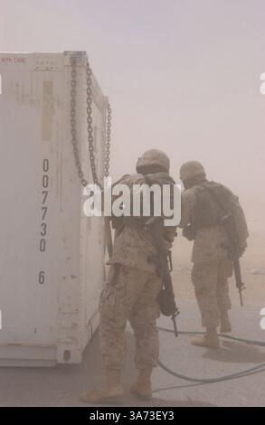 20. April 2004; Westirak, Irak; zwei Marines mit Combat Service Support Battalion 7, 1st Force Service Support Group, trotzen dem Brain-out, verursacht durch einen CH-53E Super Hengst, um die Ketten, die in einem externen Frachtzug verwendet wurden, zu einer Vorwärts-Operationsbasis im Westirak zu bringen, 20. April. Die CH-53E und ihre Besatzung gehören zur Marine Heavy Helicopter Squadron 465, Marine Aircraft Group 16, 3rd Marine Aircraft Wing. Das Geschwader stellt schwere Hebekapazitäten für alle Marineeinheiten bereit, die im Westirak operieren. Stockfoto