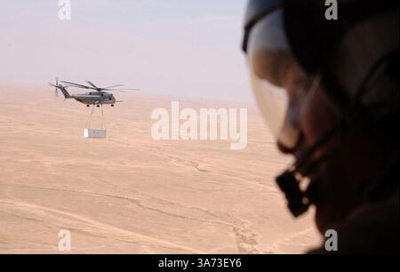 April 2004; WestIraq, Irak; Sgt. LEONARDO VELASQUEZ, Luftbeobachter, Marine Heavy Helicopter Squadron 465, Marine Aircraft Group 16, 3rd Marine Aircraft Wing aus Pomona, Kalifornien, scannt die Landschaft nach Feinden, während der führende CH-53E Super Hengst eine Ladung extern zu einem Vorwärtsflugplatz im Westirak hebt, am 20. April. Die HMH-465 und ihre Schwestergeschwader HMH-466 führen beide Schwerlasteinsätze für alle Marineeinheiten im Westirak durch. Stockfoto