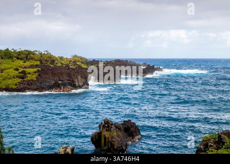 Mächtige Wellen prallen auf vulkanische Klippen in Waiianapa und zeigen die raue Schönheit der natürlichen Landschaft von Maui. Stockfoto