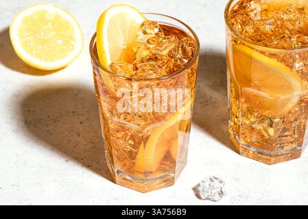 Eistee mit Zitrone. Gläser süßen Eistees mit Zitronenscheiben und zerstoßenem Eis mit trendigem Sonnenlicht. Hausgemachtes kaltes Sommergetränk. Stockfoto