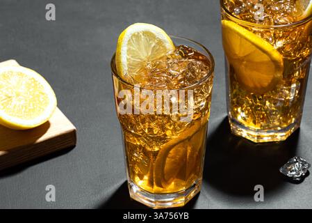 Long Island Ice Tea Cocktail Drink mit Rum. Zwei Gläser Eistee mit Zitronenscheiben und zerstoßenem Eis auf schwarzem Schiefertisch aus nächster Nähe. Hausgemachter Sommer Stockfoto