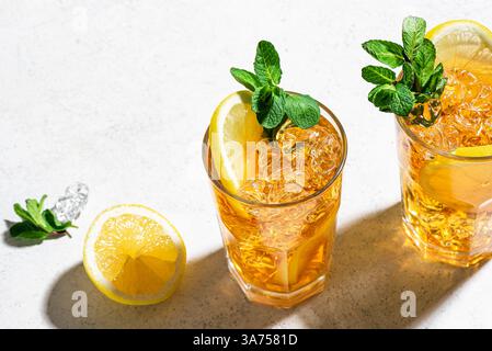 Long Island Ice Tea Cocktail Drink. Zwei Gläser Eistee mit Zitronenscheiben, Minze und Eis auf weißem Hintergrund, trendiges hartes Licht mit Schatten, obere V Stockfoto